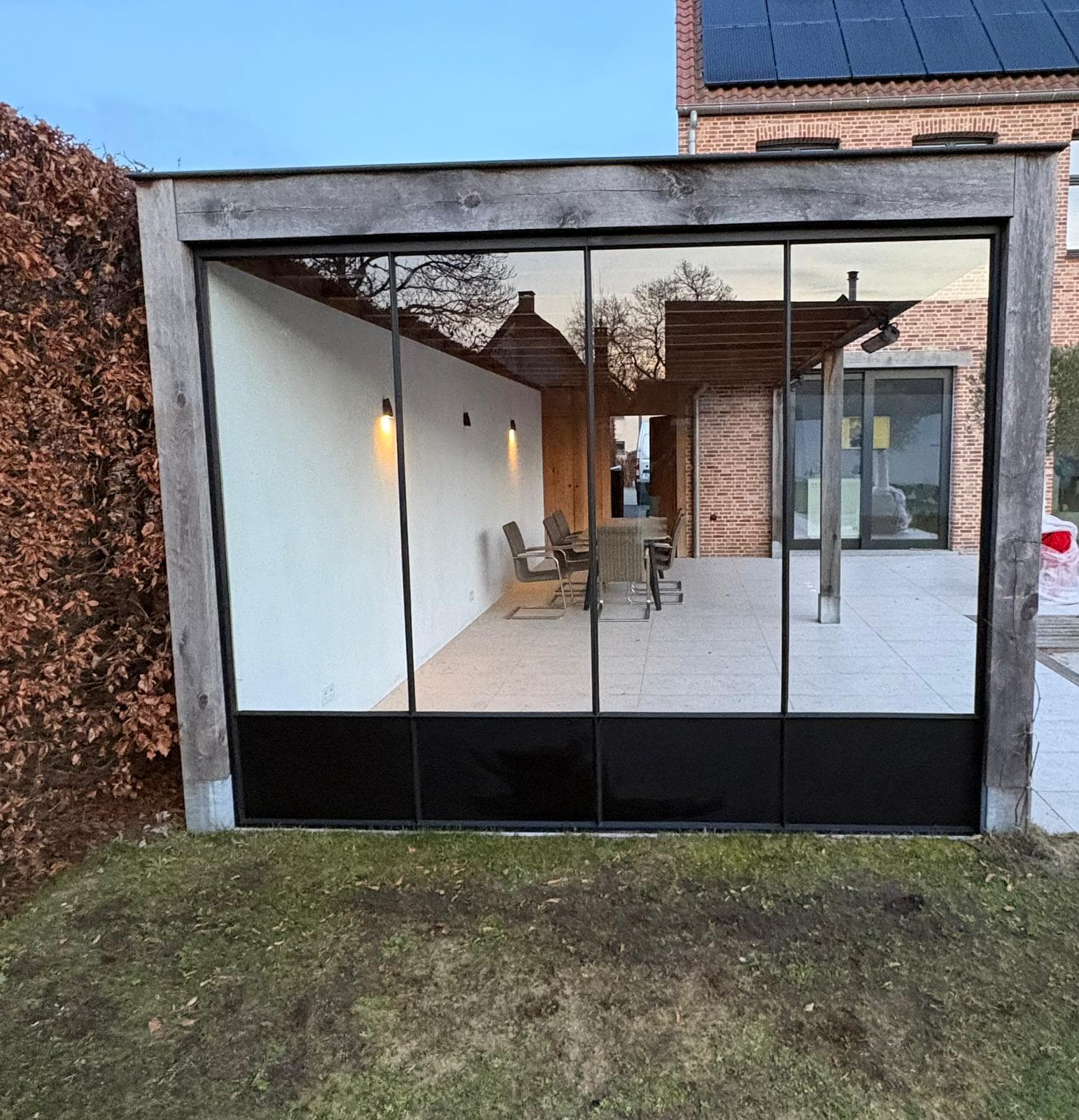Grote glazen buitenwand met houten kader in een moderne woning